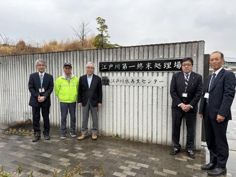 江戸川第一終末処理場の入り口前に立つ検討委員(屋外で撮影)