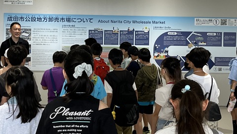 市場スタッフの説明を受ける子供たちの画像