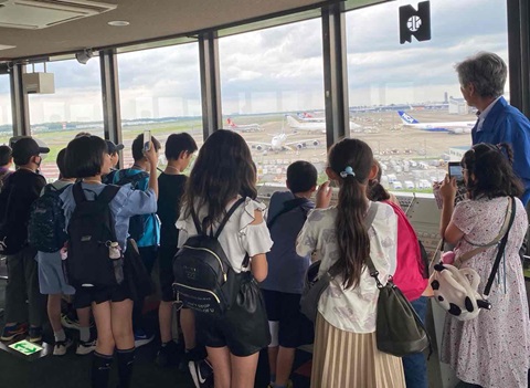 展望展示室から空港を眺める子供たちの画像