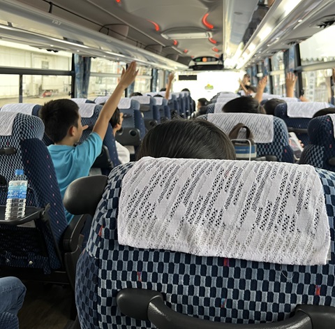 バス内でスタッフの質問に答える子供たちの画像