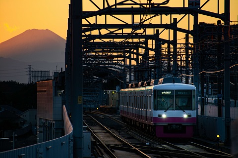 夕焼けの富士山をバックにした新京成の車両の写真
