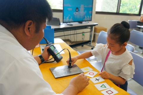 エコーで見えない絵を当てている女の子と応援する職員