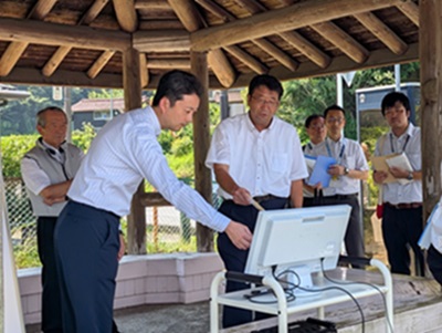 県立笠森鶴舞自然公園における現地視察の際、画面を指さしながら町長の説明を聞く知事の画像