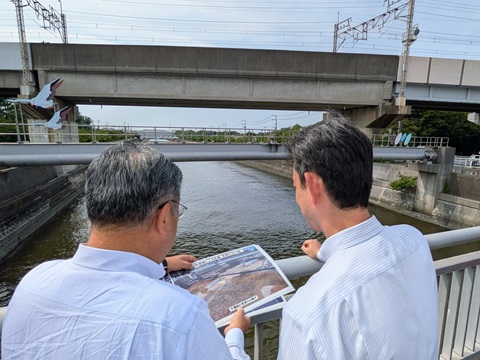 見明川河口部における現地視察の際、川沿いで市長の説明を聞く知事の画像